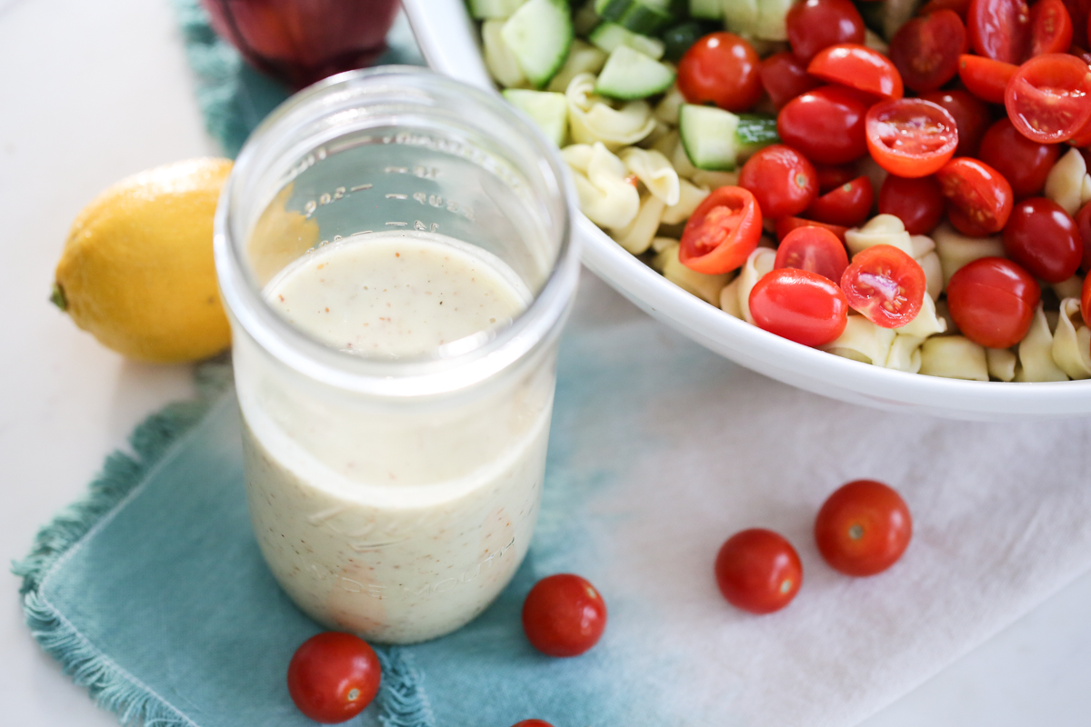 Ground Mustard Vinaigrette in a jar next to a pasta salad