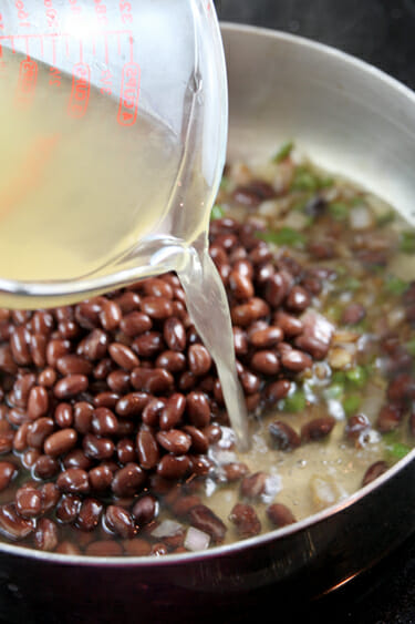 pouring chicken broth black beans with chicken stock