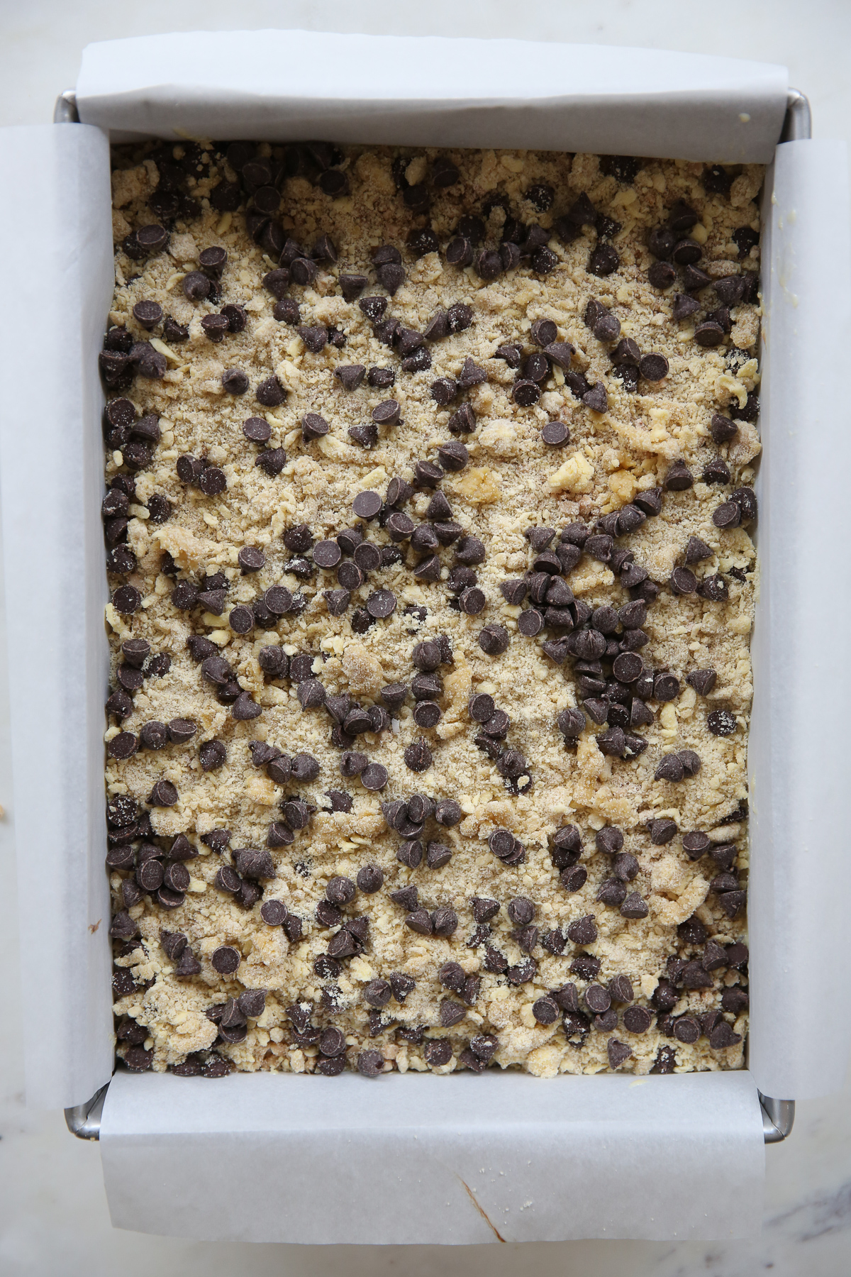 layered cookie bar ingredients in a baking pan