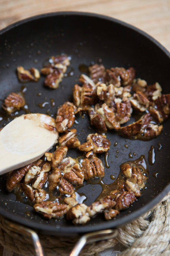 Candied walnuts in sugary syrup in a skillet. 