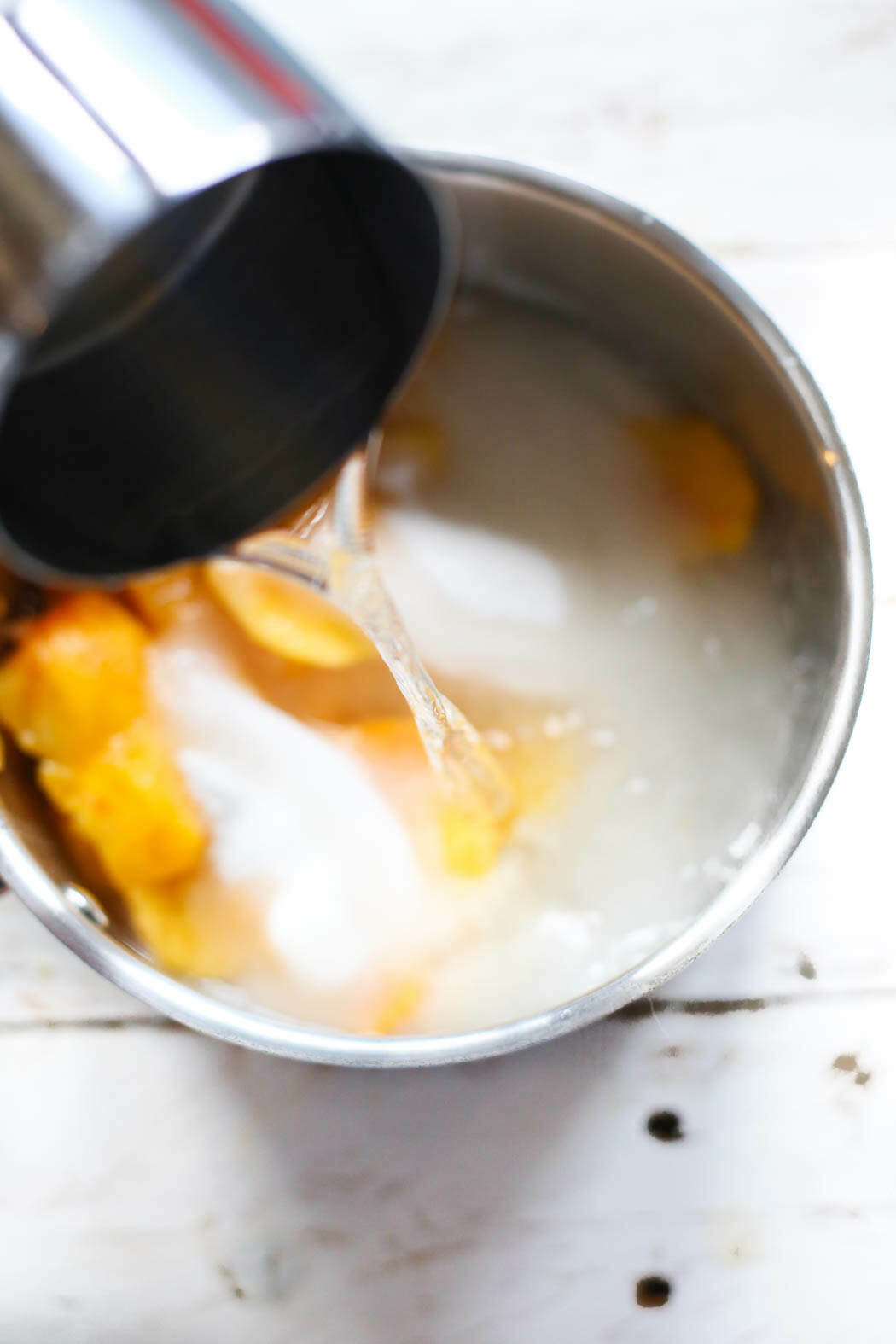 adding water to sugar and peaches for peach syrup