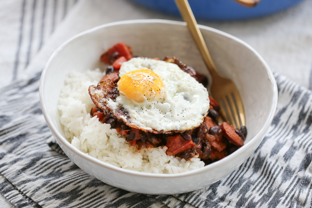 black bean and kielbasa skillet in a bowl over rice with a fried egg on top