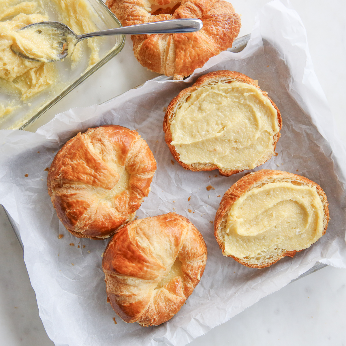 croissants on a baking sheet with almond cream spread in the middle