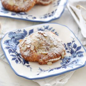 almond croissant dusted in powdered sugar on a blue and white plate