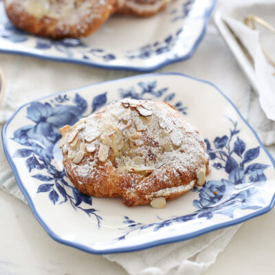 almond croissant dusted in powdered sugar on a blue and white plate