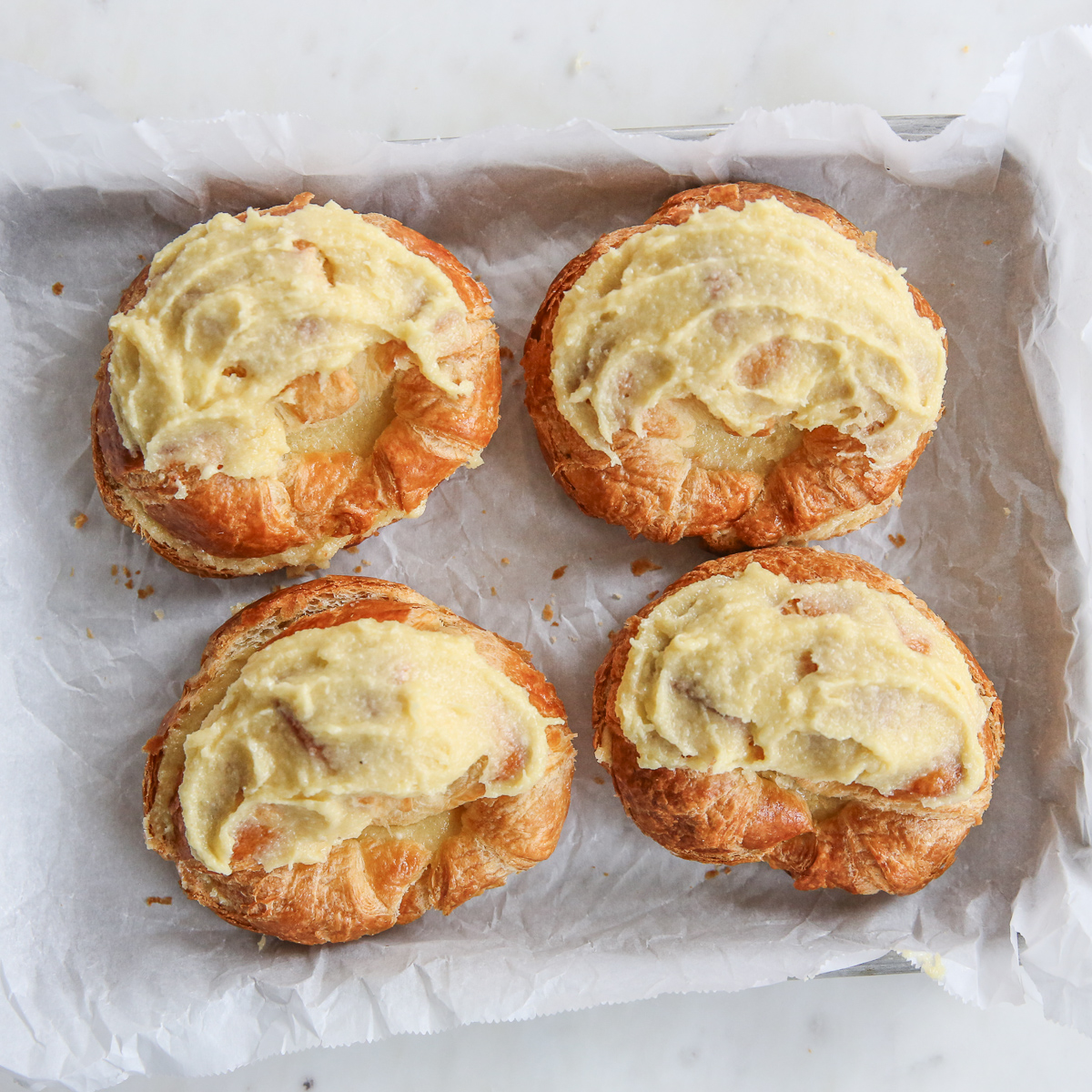 croissants on a baking sheet with almond cream on top