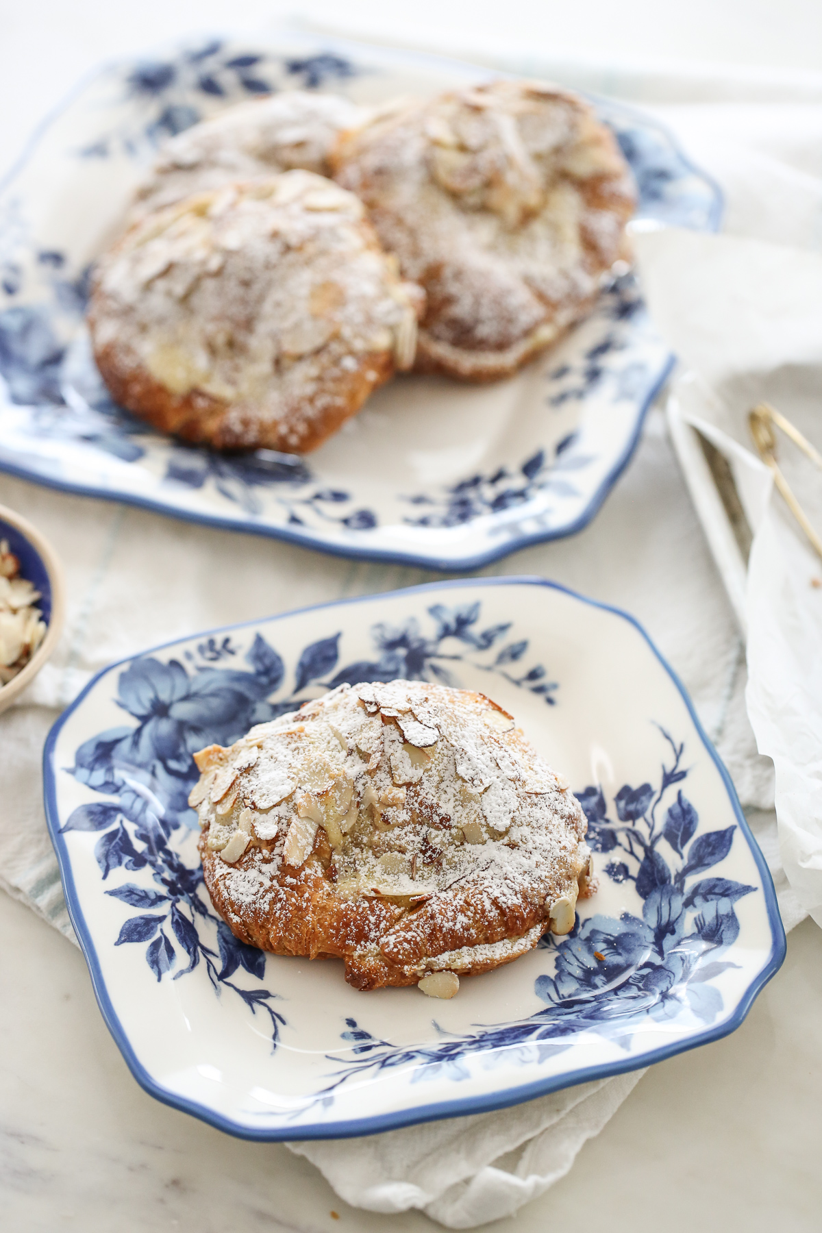 almond croissant dusted in powdered sugar on a blue and white plate