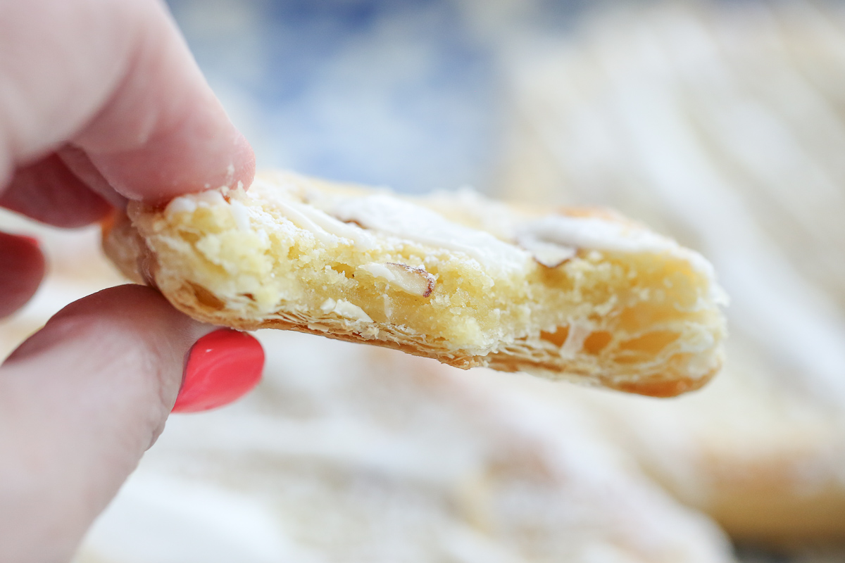 Almond danish pastry broken in half with filling inside and sliced almonds on top